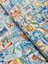 Coastal cotton fabric featuring beach-themed words, seashells, sand dollars, and nautical typography in blue, tan, and white tones.