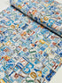 Coastal cotton fabric featuring beach-themed words, seashells, sand dollars, and nautical typography in blue, tan, and white tones.