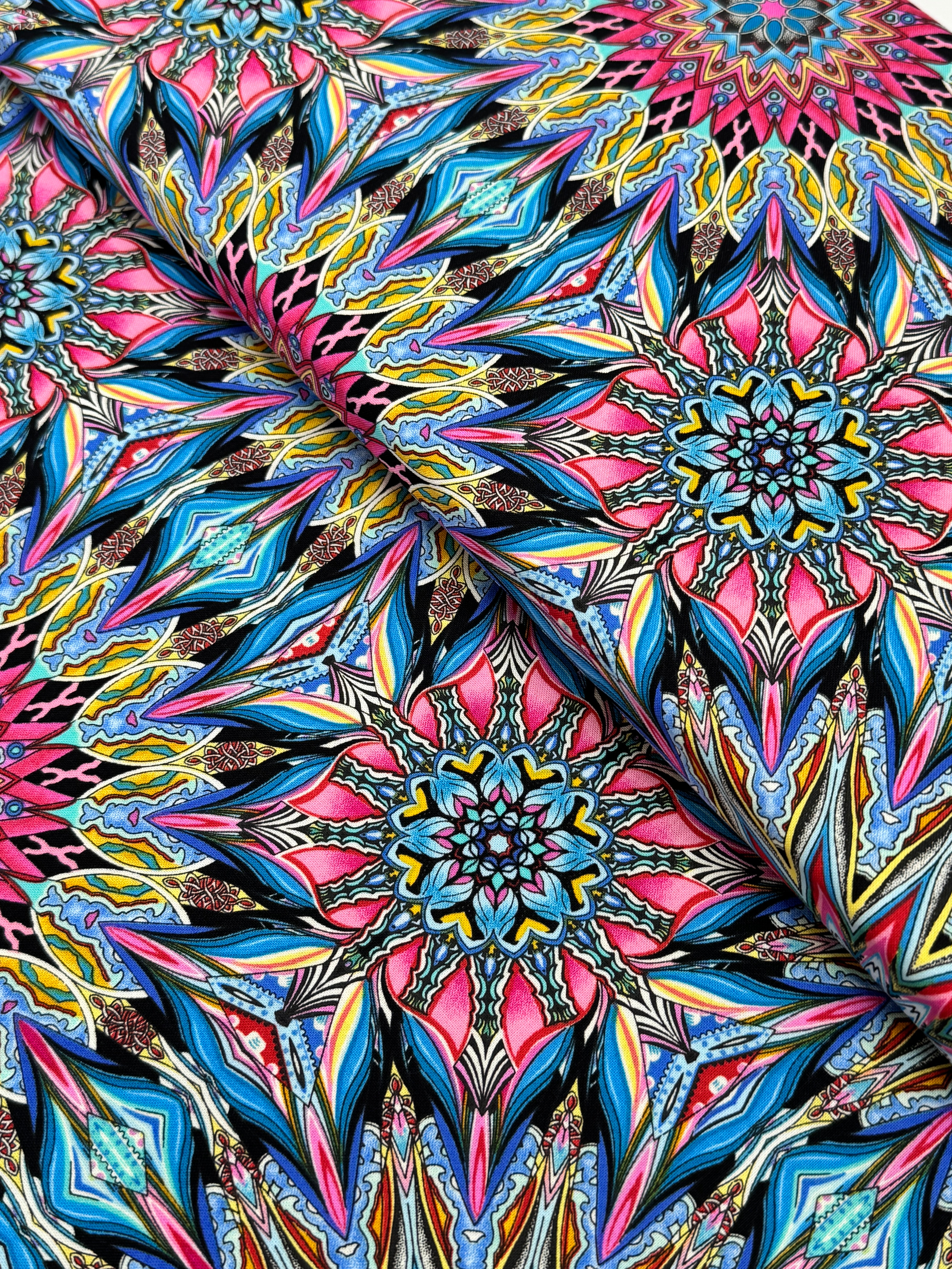 Where in the World Rio Blue Multi cotton fabric by Paula Nadelstern featuring colorful kaleidoscope medallions in blue pink yellow and black.