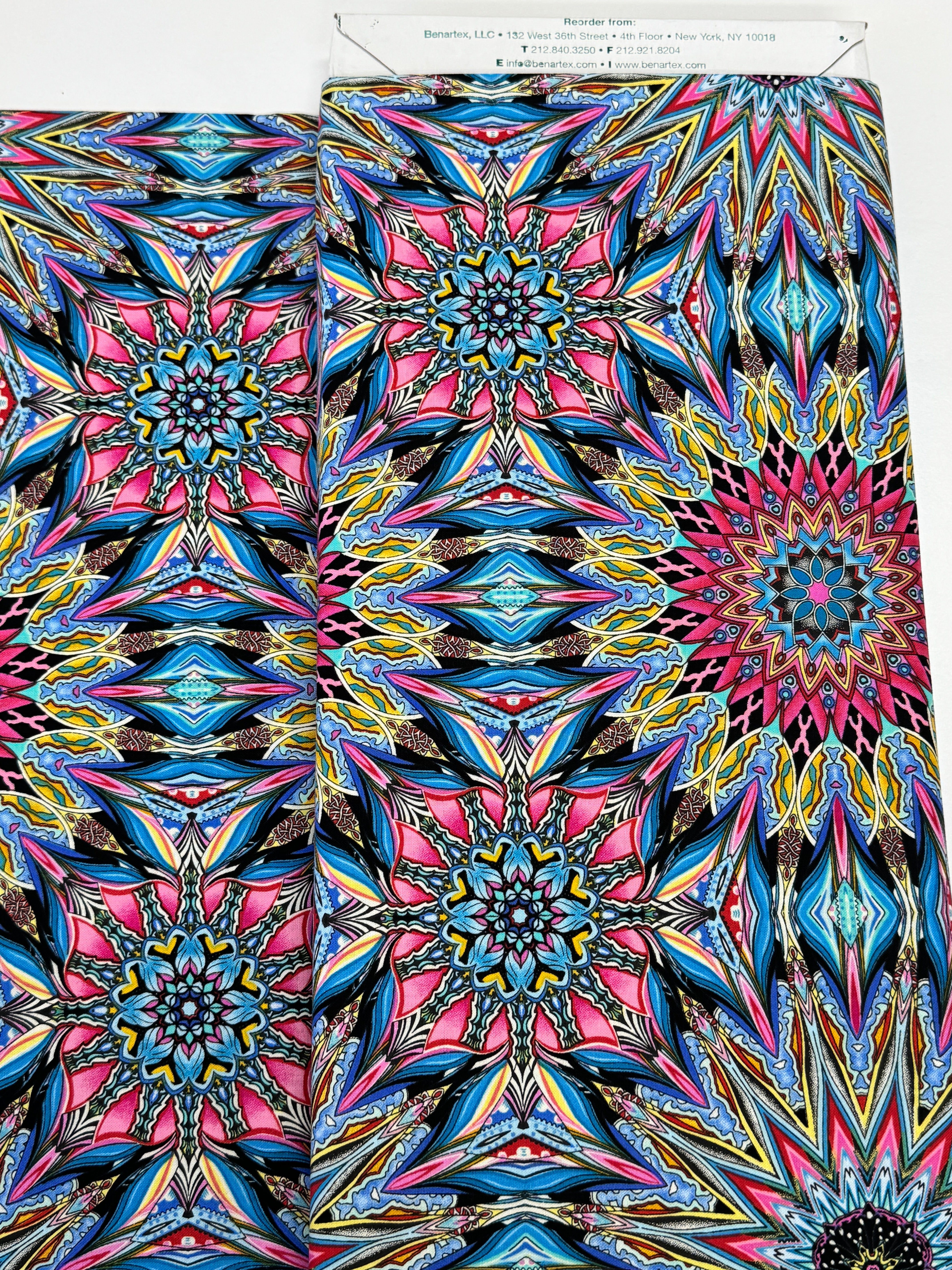 Where in the World Rio Blue Multi cotton fabric by Paula Nadelstern featuring colorful kaleidoscope medallions in blue pink yellow and black.