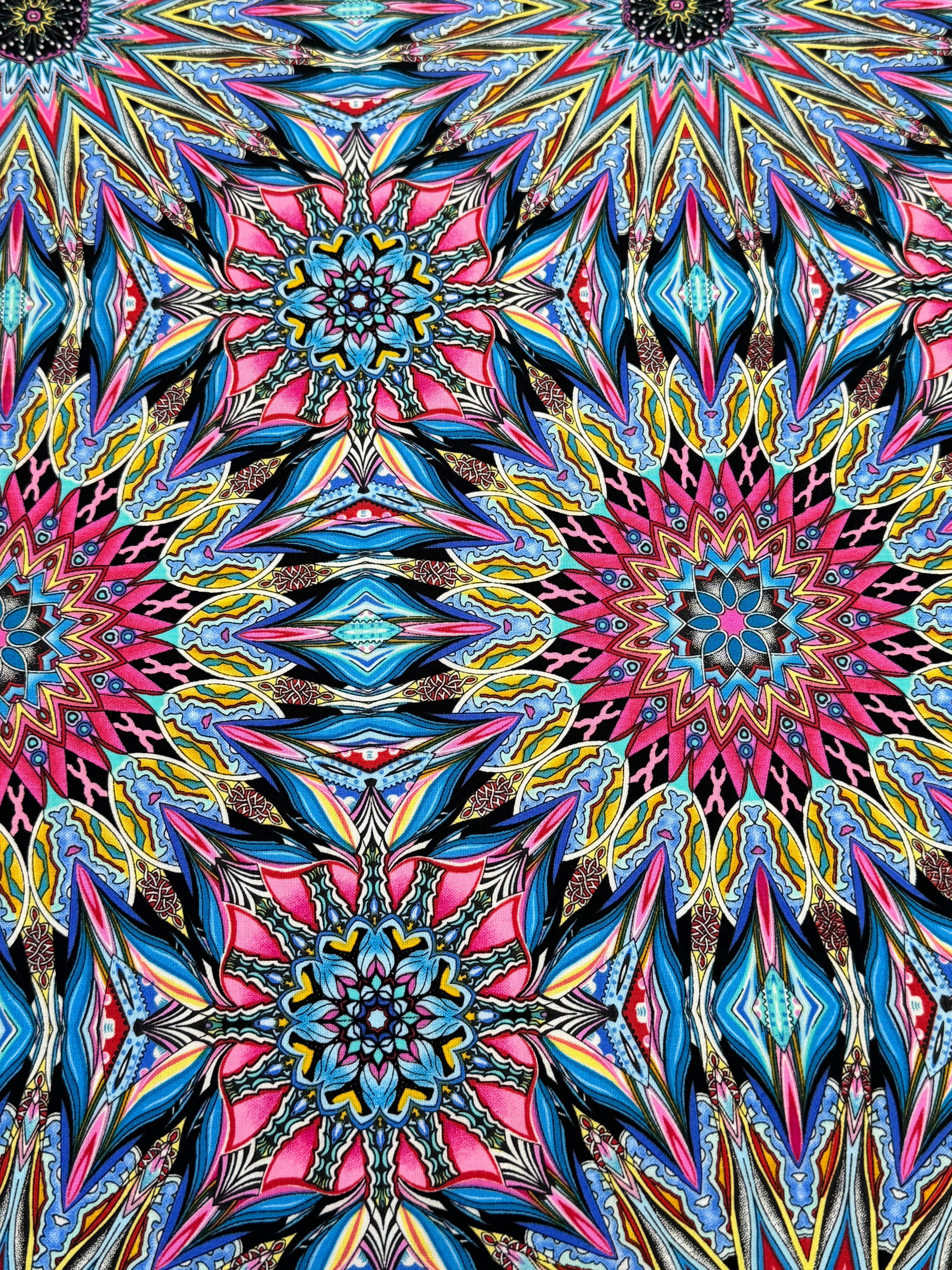 Where in the World Rio Blue Multi cotton fabric by Paula Nadelstern featuring colorful kaleidoscope medallions in blue pink yellow and black.