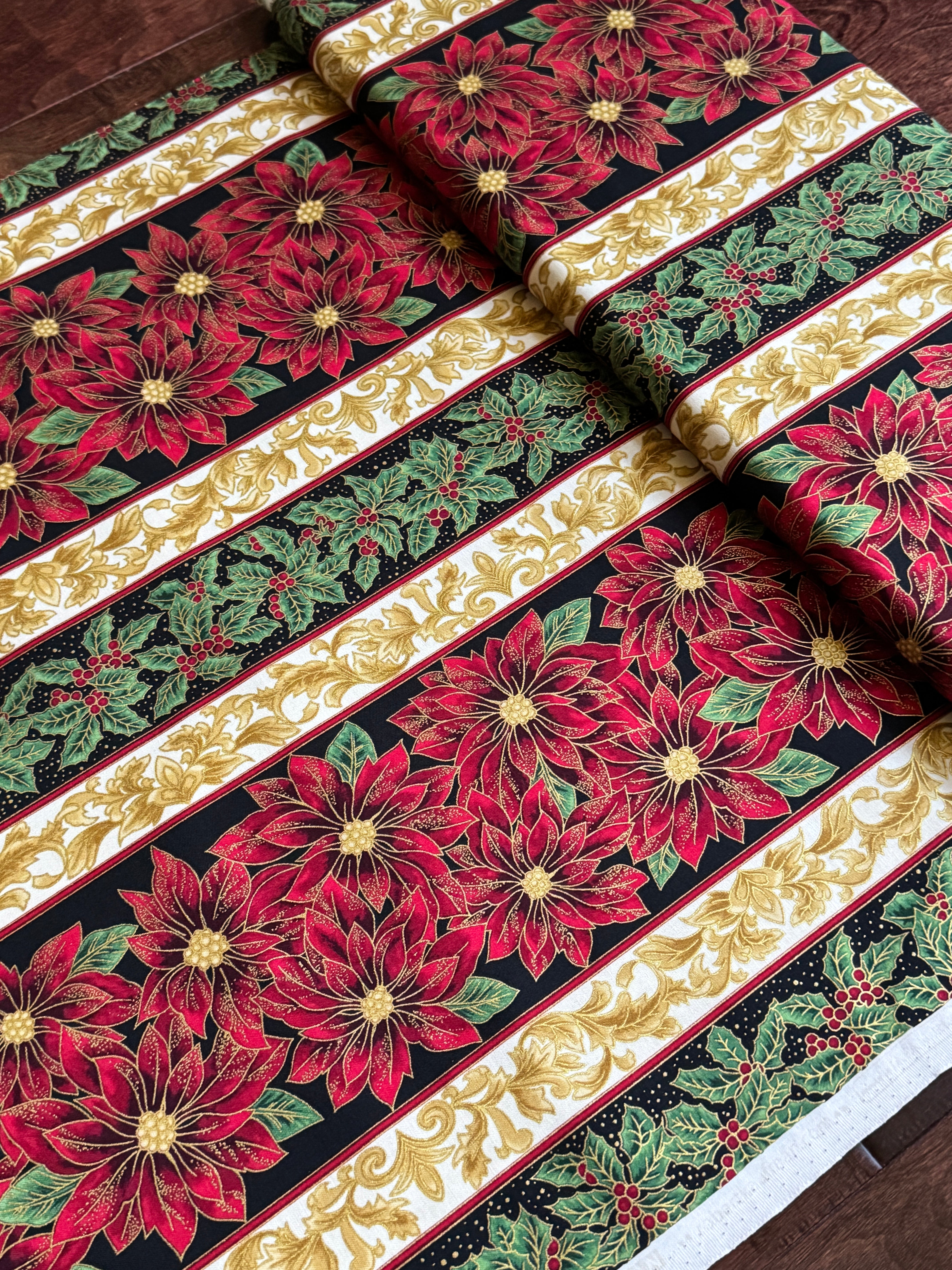 Holiday Flourish 12 poinsettia stripe black metallic fabric featuring red poinsettias, holly leaves, and gold scrollwork by Peggy Toole for Robert Kaufman.