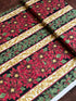 Holiday Flourish 12 poinsettia stripe black metallic fabric featuring red poinsettias, holly leaves, and gold scrollwork by Peggy Toole for Robert Kaufman.