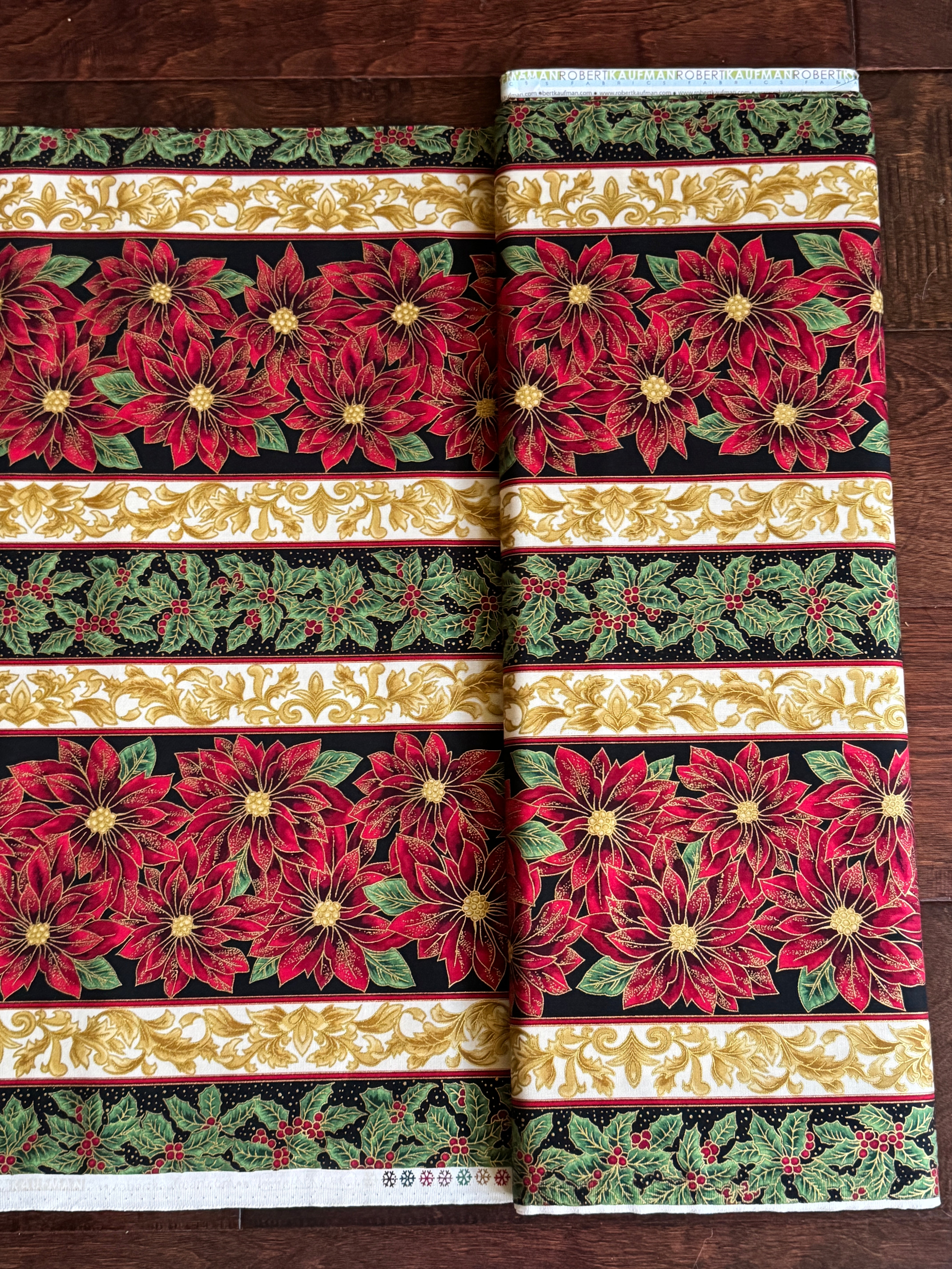 Holiday Flourish 12 poinsettia stripe black metallic fabric featuring red poinsettias, holly leaves, and gold scrollwork by Peggy Toole for Robert Kaufman.
