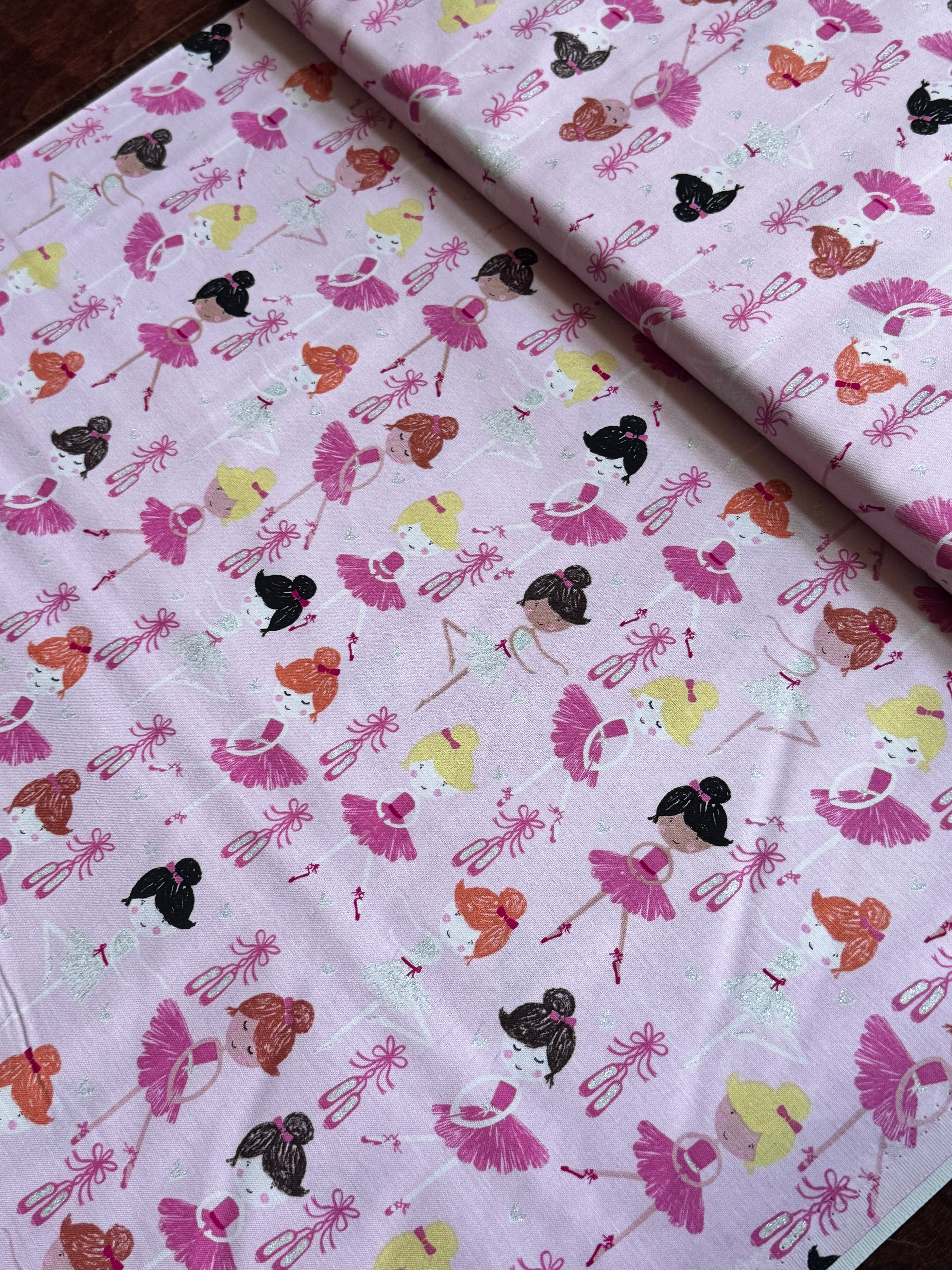 Pink cotton fabric featuring tossed ballerinas, tutus, ballet shoes, and silver glitter accents by Timeless Treasures.