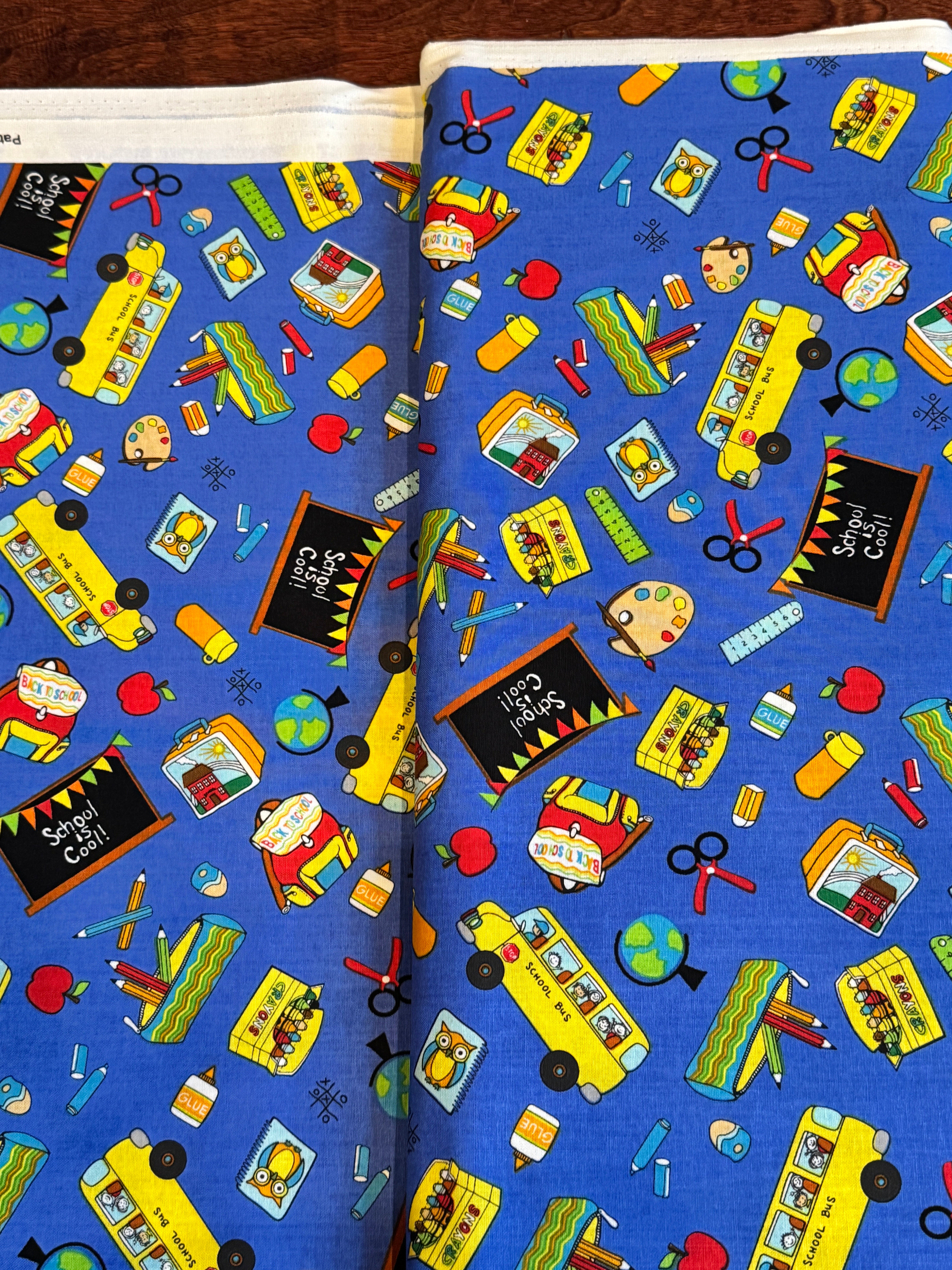 Blue School Rules cotton fabric featuring school buses, crayons, apples, chalkboards and classroom supplies by Blank Quilting.