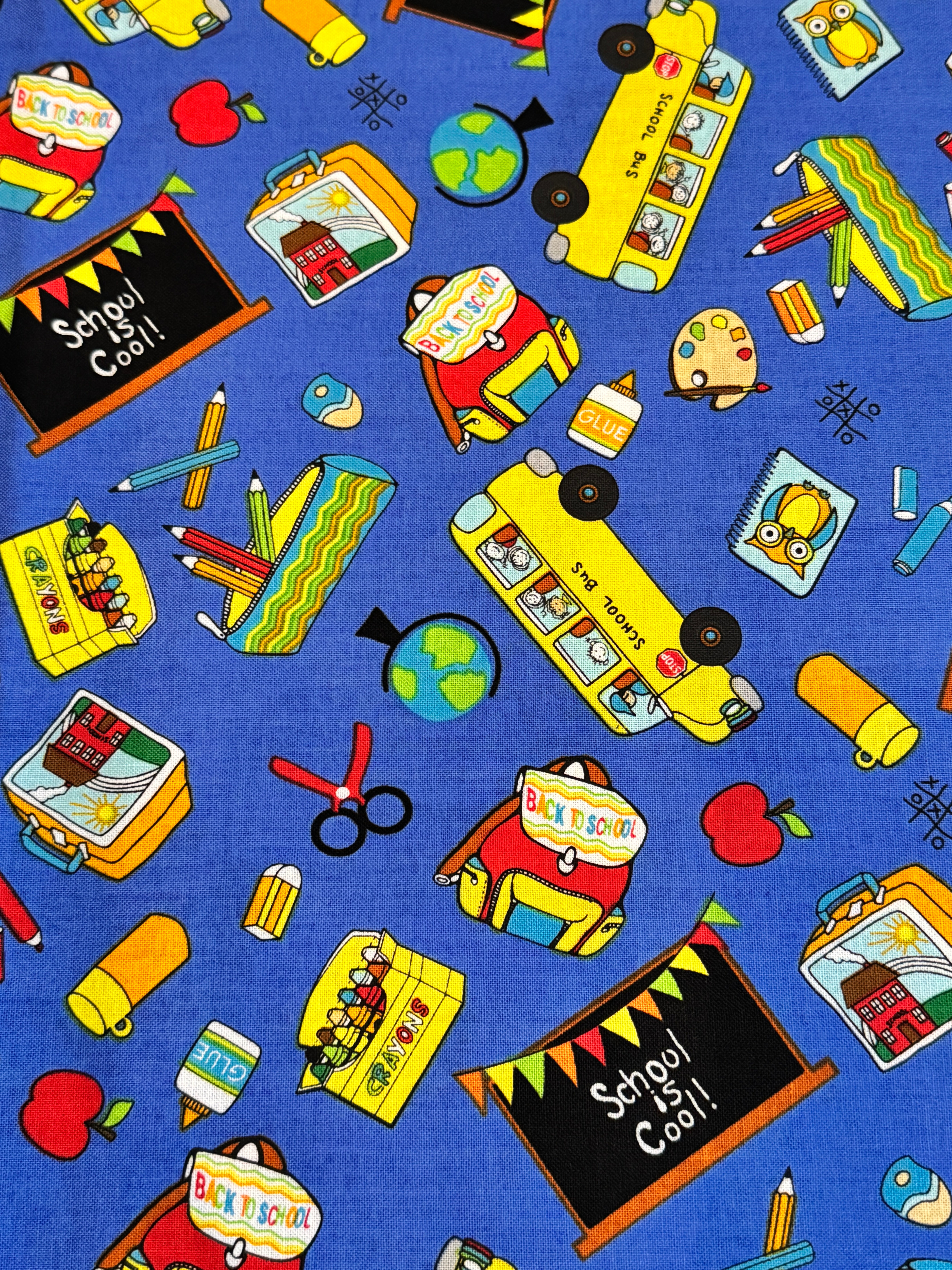 Blue School Rules cotton fabric featuring school buses, crayons, apples, chalkboards and classroom supplies by Blank Quilting.