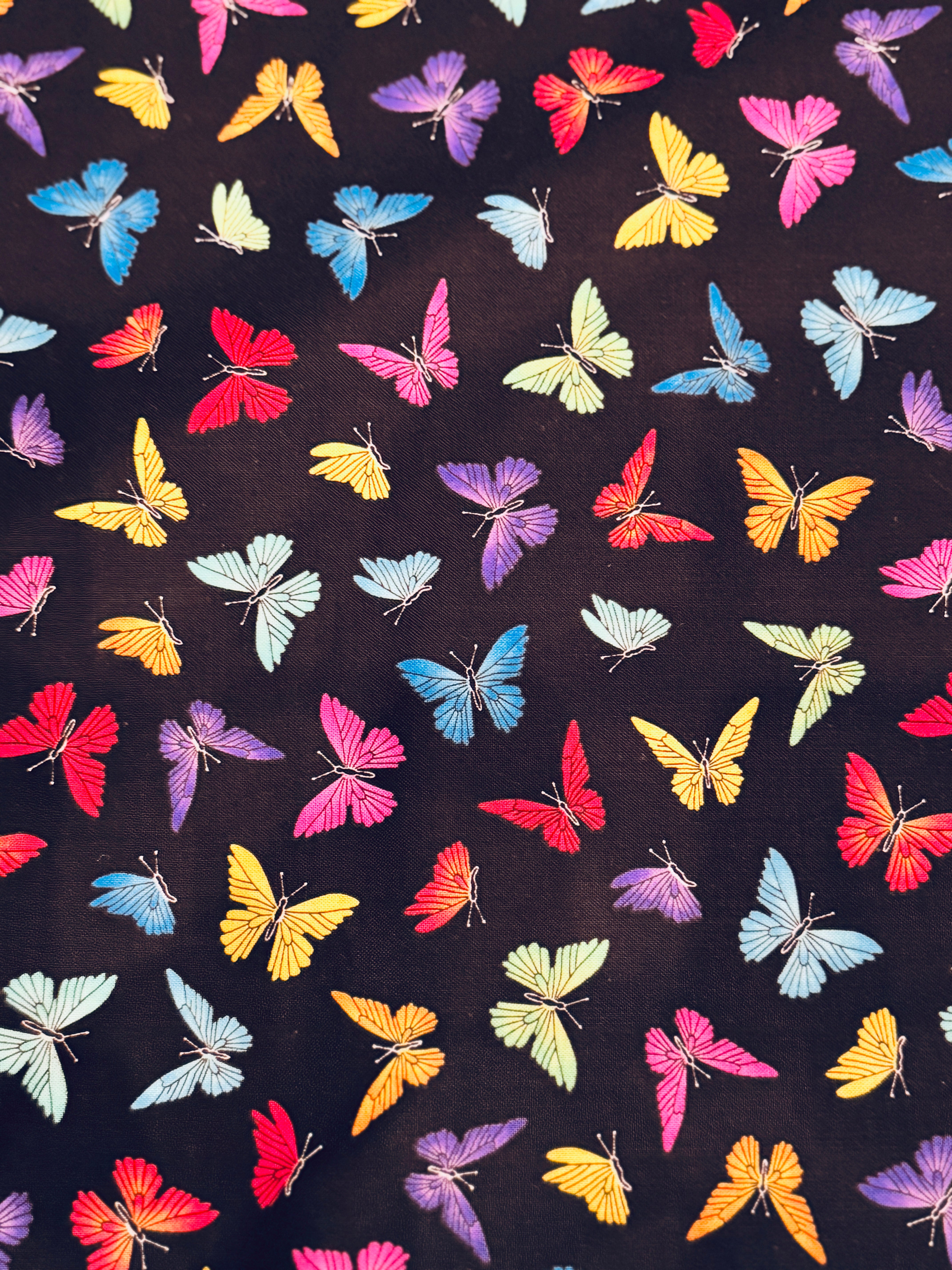 Colorful rainbow butterflies scattered on a black background fabric by Chong-A Hwang for Timeless Treasures.