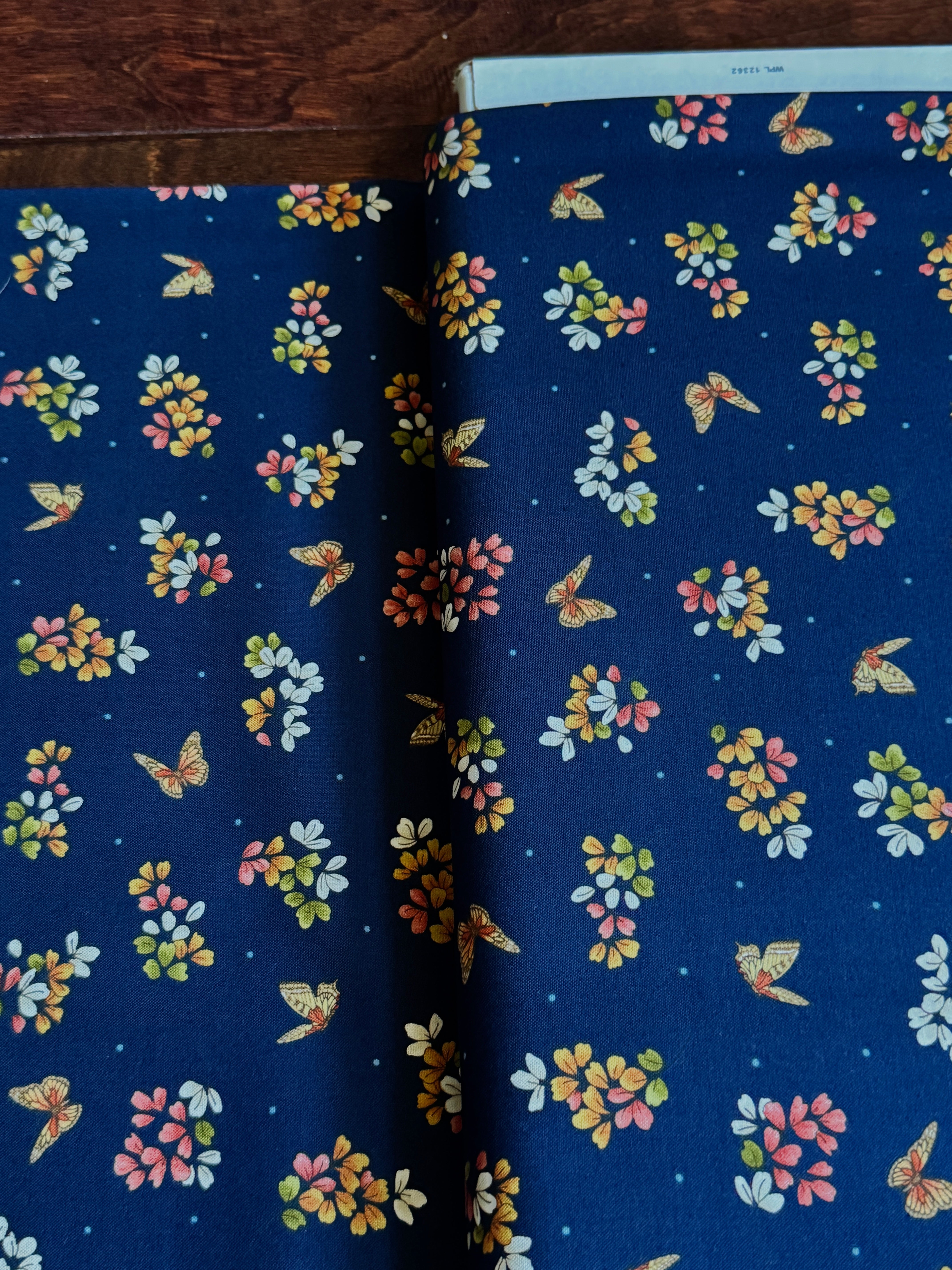 Navy cotton fabric featuring delicate floral blossoms and butterflies scattered throughout, from the Japanese Garden collection by Maywood Studio.