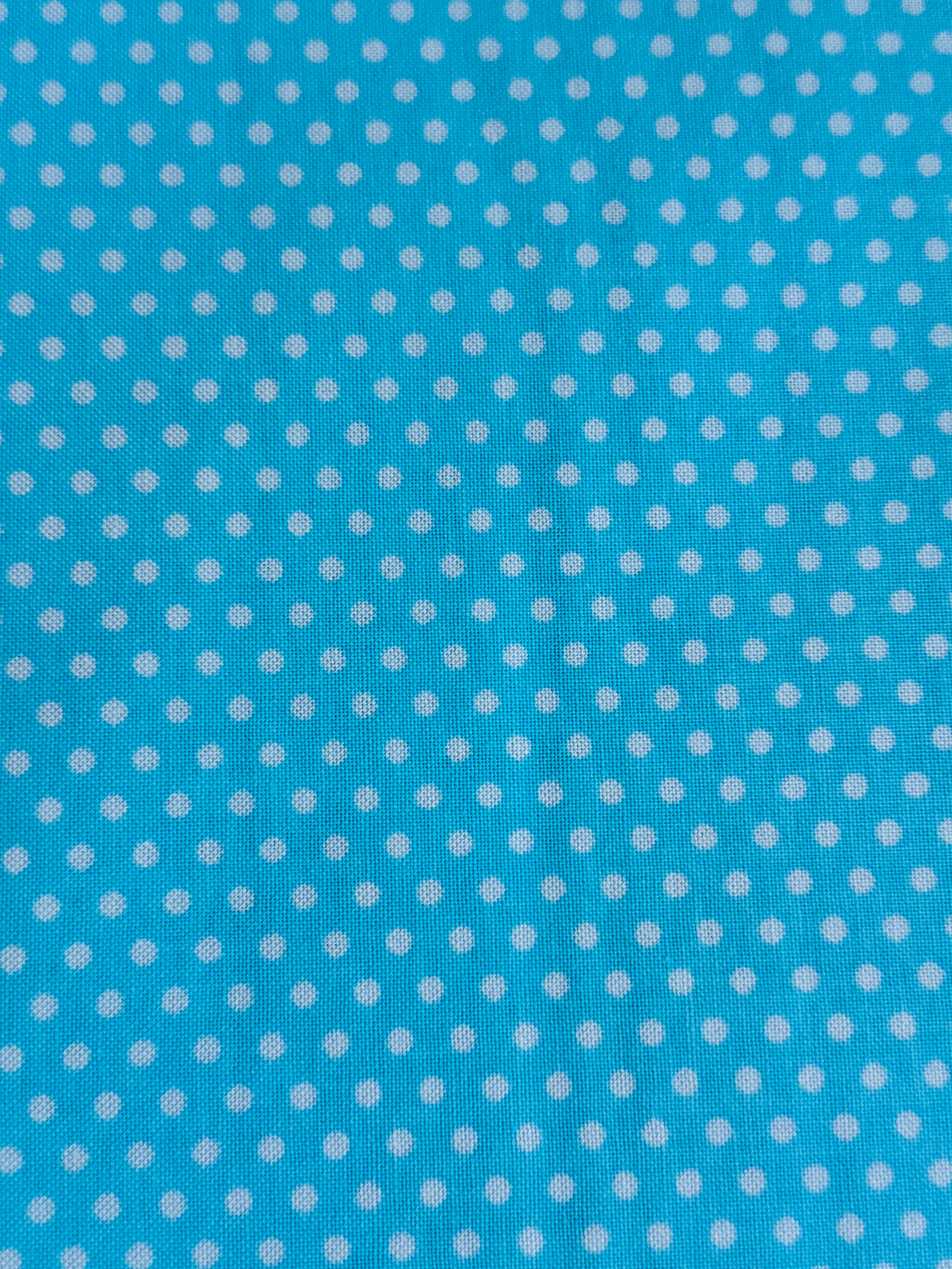 Aqua blue cotton fabric featuring small white polka dots in an all-over pattern by Robert Kaufman Fabrics, ideal for quilting, sewing, nursery décor, and craft projects.
