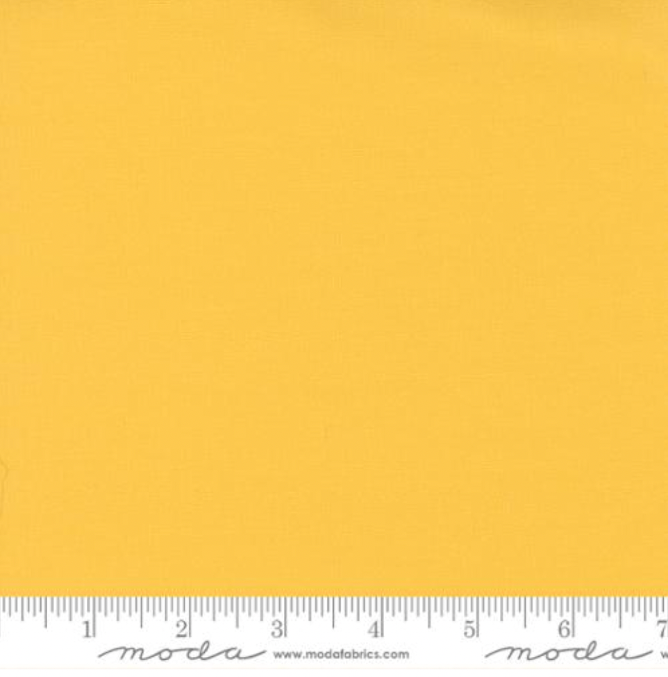 Bella Solids Buttercup Fabric by Moda Fabrics – bright yellow 100% cotton quilting fabric shown with ruler for scale.