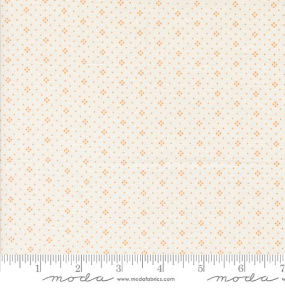 A close-up of Agatha Road – Eyelet Ivory Orange Dot Foulard Fabric by Fig Tree & Co for Moda Fabrics, featuring small orange dot clusters on an ivory cotton background, ideal for quilting and sewing projects.