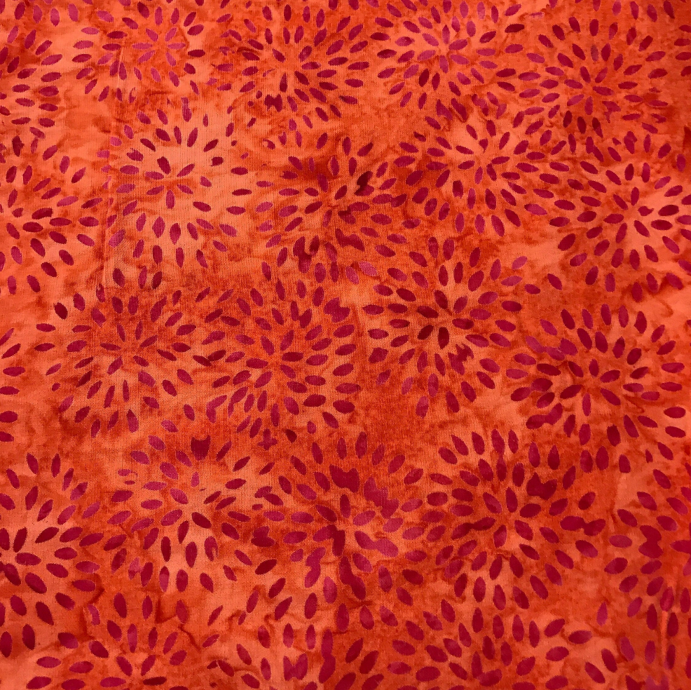 Red and orange batik fabric featuring dahlia-inspired floral bursts by Island Batik.