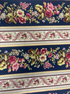 Bricolage Navy Border Stripe fabric by Kaye England for Wilmington Prints featuring elegant floral garlands and decorative border stripes in pink, burgundy, cream, and green on a rich navy background.