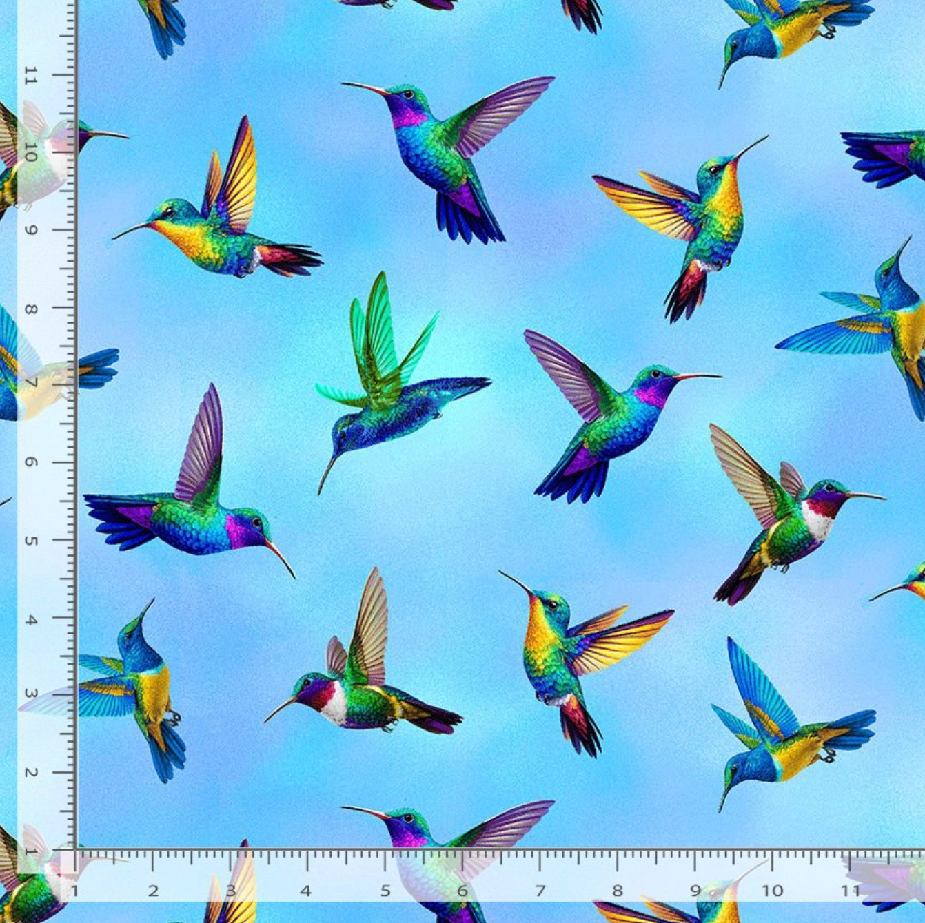 Flying Hummingbirds Blue fabric by Chong-A Hwang for Timeless Treasures featuring colorful hummingbirds in flight on a soft sky-blue background with vibrant jewel-tone details.