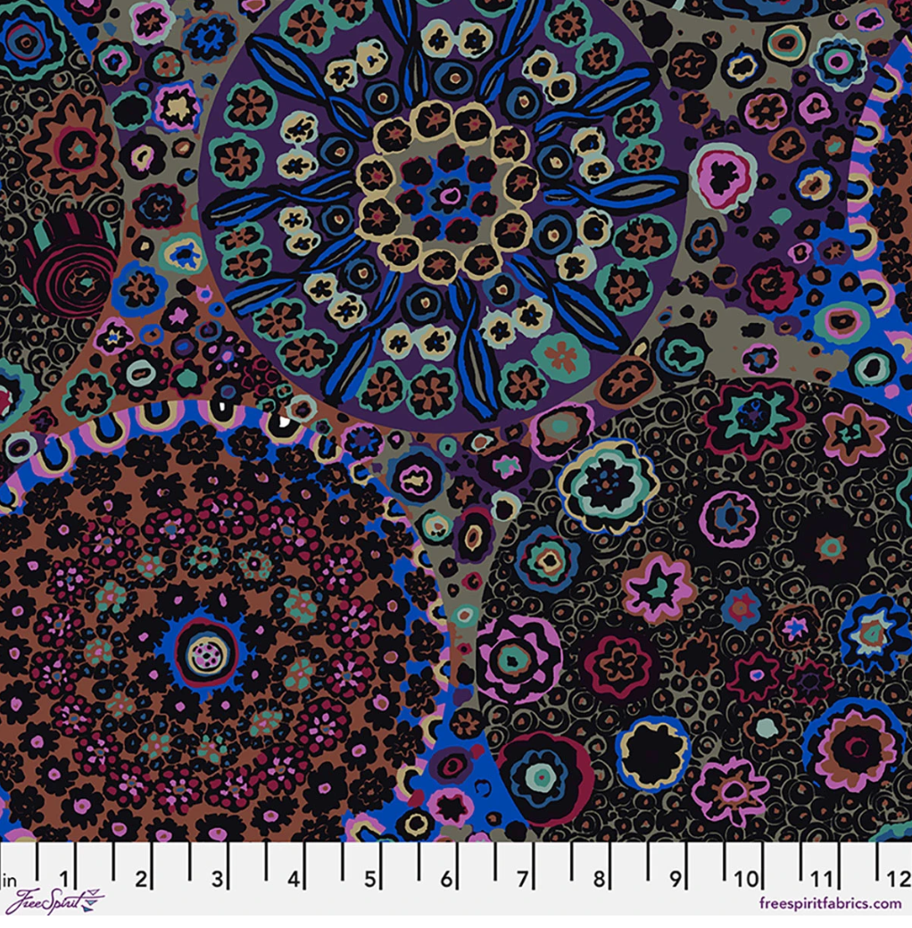 Kaffe Fassett Millefiore Dark cotton lawn fabric featuring large circular floral motifs in black, purple, blue, magenta, teal, rust, and olive tones.