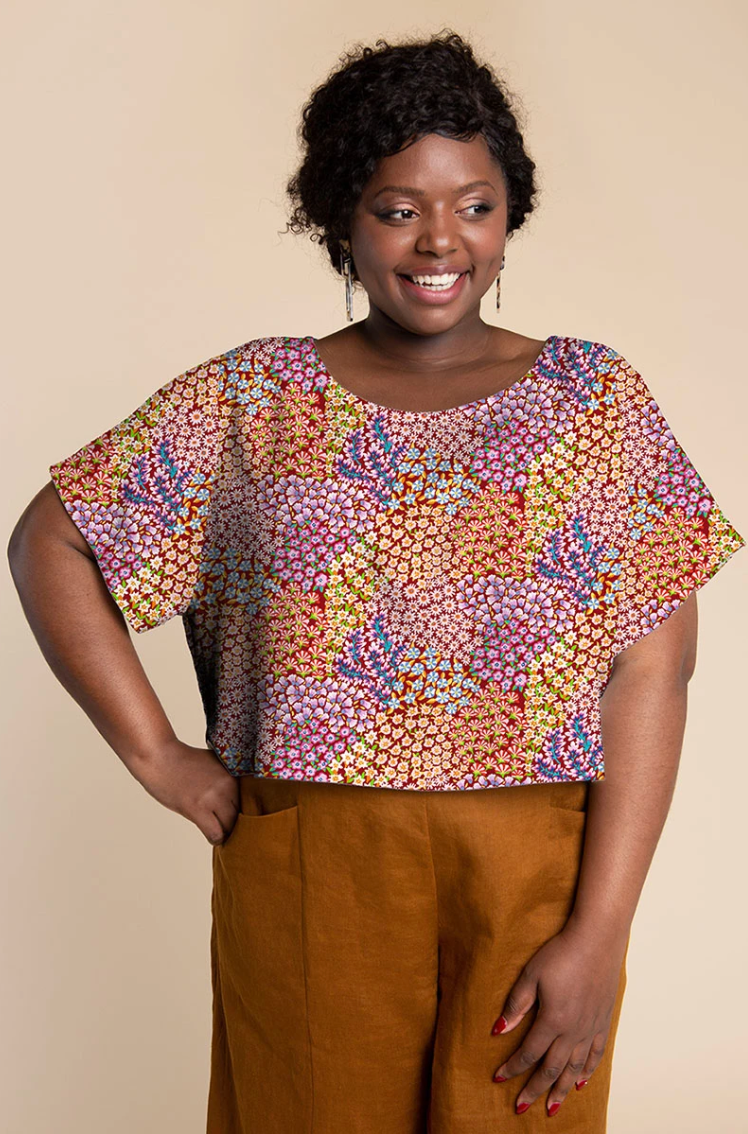 Woman wearing a loose top made with Kaffe Fassett Persian Garden Rust cotton lawn fabric featuring colorful clustered floral motifs.