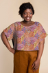 Woman wearing a loose top made with Kaffe Fassett Persian Garden Rust cotton lawn fabric featuring colorful clustered floral motifs.