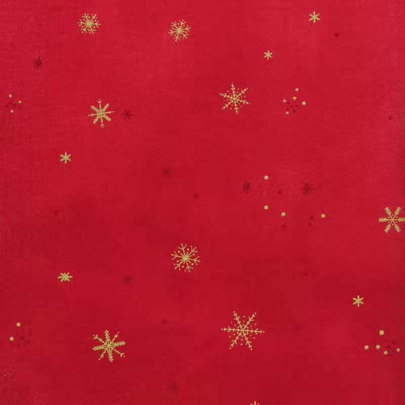 A vibrant red fabric from the Ombre Flurries Metallic collection by V and Co. for Moda Fabrics, featuring shimmering gold metallic snowflakes scattered across the surface.