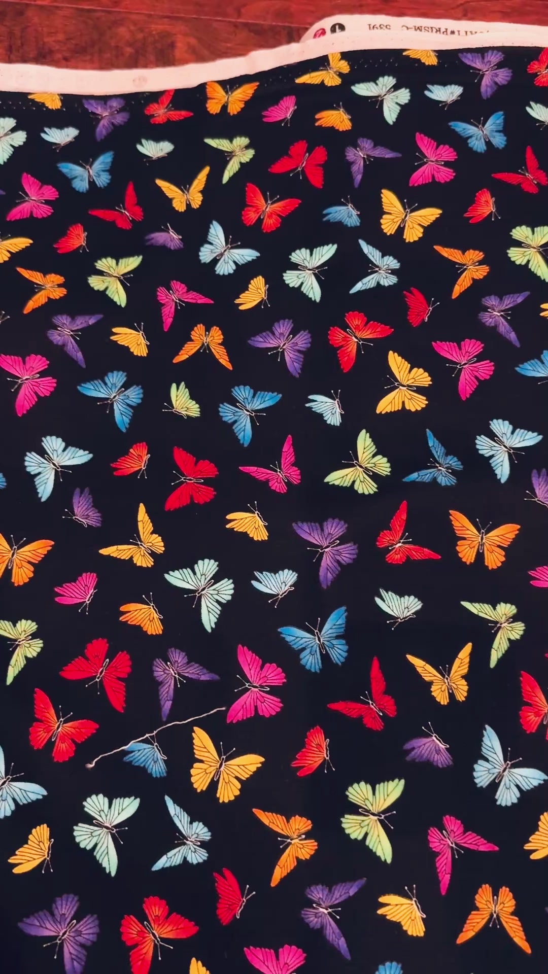Colorful rainbow butterflies scattered on a black background fabric by Chong-A Hwang for Timeless Treasures.