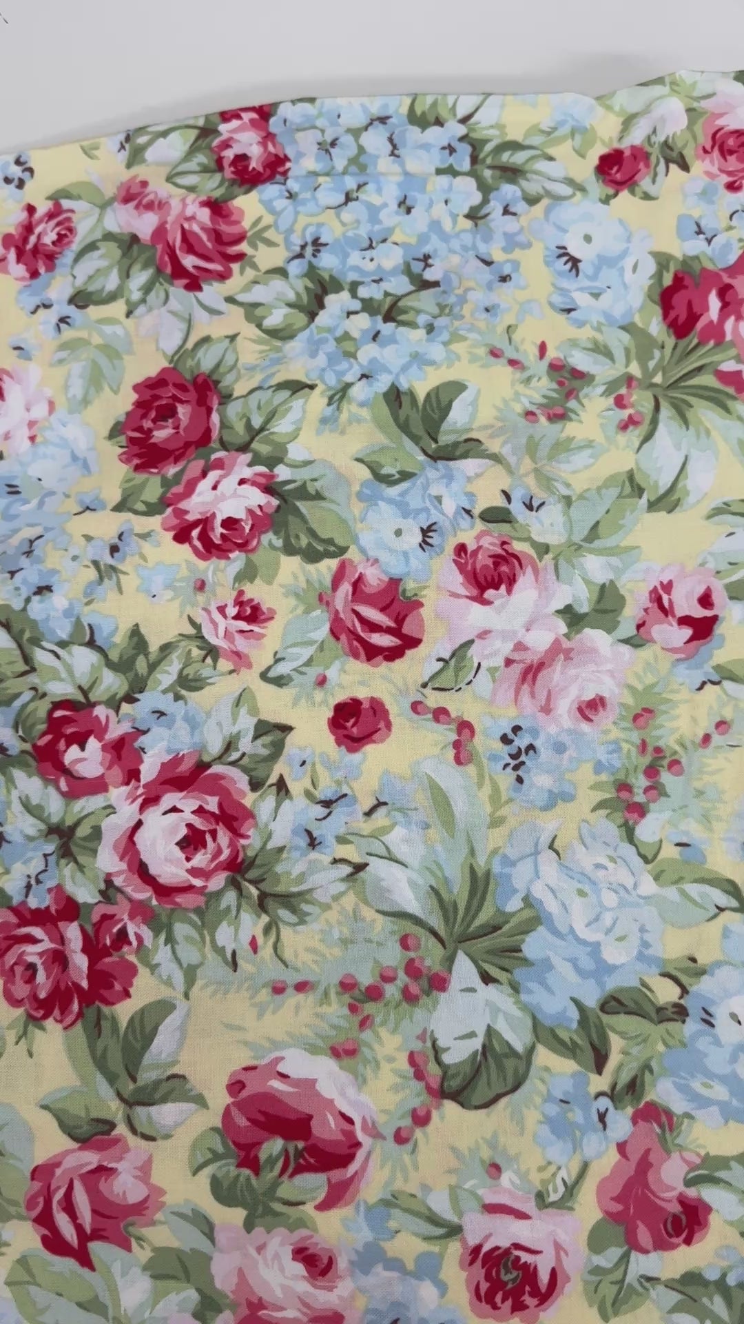 Floral cotton fabric featuring pink roses, blue hydrangeas, and delicate blossoms on a soft butter yellow background from the Simply Chic collection by Anna Stuart for Benartex.