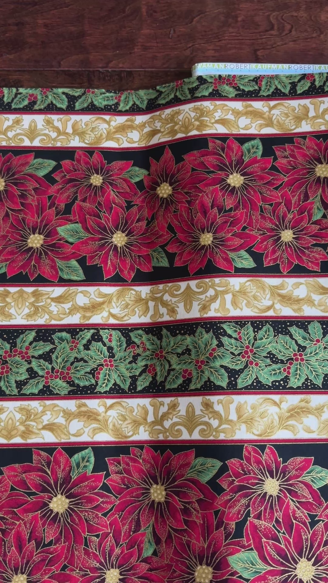 Holiday Flourish 12 poinsettia stripe black metallic fabric featuring red poinsettias, holly leaves, and gold scrollwork by Peggy Toole for Robert Kaufman.